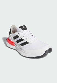 White athletic sneaker with black accents and three stripes. Features a textured upper, padded tongue, and red detailing on the heel.