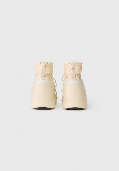 Beige quilted ankle boots with drawstring closure, thick rubber sole, and lace detailing, viewed from the back on a white background.