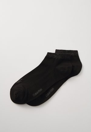 Chaussettes noires de cheville en matériau lisse, avec un haut élastique gris contrastant et une marque sur le côté.