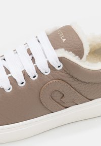 Baskets en cuir taupe avec lacets blancs, doublure en peau lainée crème et détail du logo embossé sur le côté et la languette.