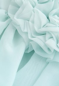 Tissu bleu clair doux avec des volants délicats et superposés créant un motif fluide et texturé.
