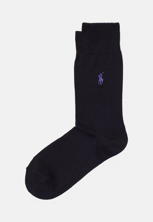 Chaussettes noires en textile lisse ; avec un poignet côtelé et un petit logo violet.