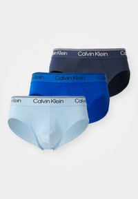 Drei Calvin Klein Herren-Briefs in Hellblau, Königsblau und Marineblau, jeweils mit einem elastischen Bund mit Markenlogo.