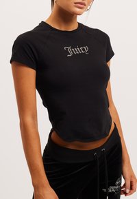 Čierne skrátené tričko s krátkymi rukávmi a okrúhlym výstrihom. Na prednej strane má text „Juicy“ posiaty kamienkami. Hladká, elastická tkanina.