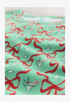 Žalia rištuota medžiaga su pasikartojančiu raudonų juostelių ir šventinių kokteilių raštu, pabrėžtu tokiais akcentais kaip dryžuotos šiaudeliai ir vyšnios.