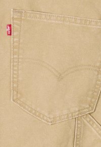 Τσέπη από μπεζ τζιν με διπλή ραφή και μια μικρή κόκκινη ετικέτα Levi's στην αριστερή πλευρά.