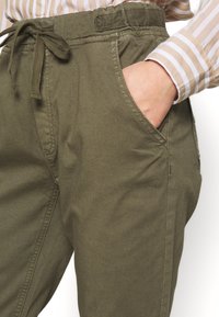 Olijfgroene, lichtgewicht broek met een trekkoord in de taille, zijzakken en een gladde textuur. Kenmerkt zich door minimale stiksels en eenRelaxed fit.