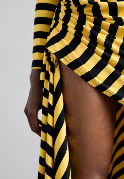 Svart och gulrandig klänning med samlad tyg och en hög slits, som visar upp en mjuk textur och en figursydd design.