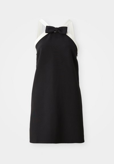 Vestido negro sin mangas con tirantes blancos y un detalle de lazo en el escote. Textura suave, diseño hasta la rodilla. Silueta sencilla y elegante.