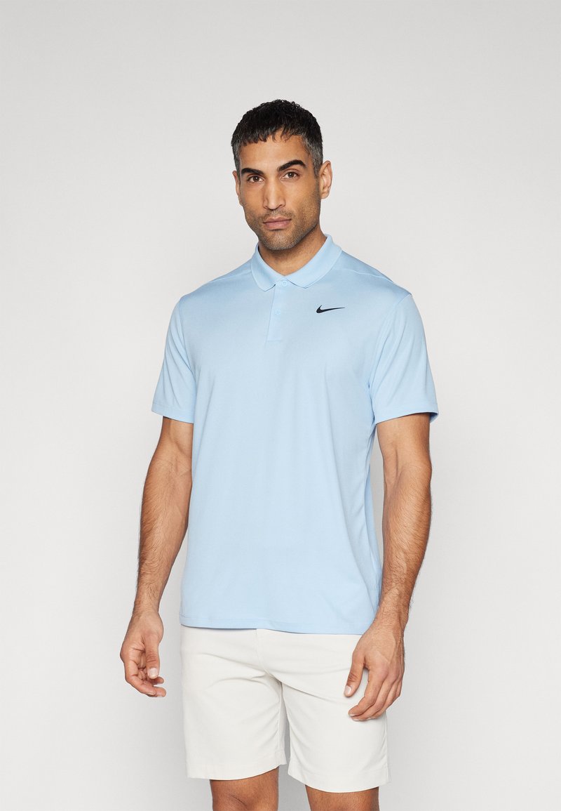 T-shirt polo azul claro feito de tecido suave, com um logo preto da Nike no lado esquerdo do peito, mangas curtas e um design de colarinho clássico.