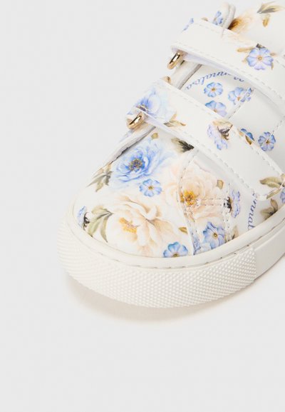 Fehér virágmintás sneaker kék és krémszínű virágokkal, két tépőzáras pánttal, texturált gumitalppal és aranyszínű fémelemekkel.