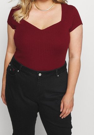 Bordeaux ribbet bodysuit med V-hals, parret med højtsiddende sorte denim bukser med kontrastsyninger og sølvknapper.