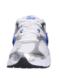 Sneaker bianco con accenti argentati, dettagli blu, materiali in rete e sintetici, linguetta imbottita e suola in gomma nera testurizzata.