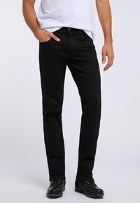 Czarne dżinsy o slim fit, wykonane z denimu. Posiadają pięć kieszeni i zapięcie na guzik, zestawione z czarnymi butami. Prosty design.