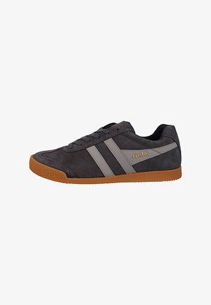 Gray suede sneaker with gum outsole, featuring two horizontal light gray stripes and branded accent. Low-profile design and lace-up closure.