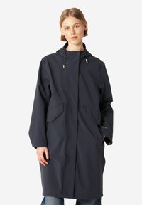 Granatowy wodoodporny płaszcz z kapturem, z przednimi kieszeniami, z zapięciem na napy i luźnym krojem. Gładka faktura z minimalnymi detalami.