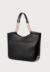 Black leather tote bag with a pebbled texture, dual handles, gold chain accents, and a logo detail on the side. Curved top opening.