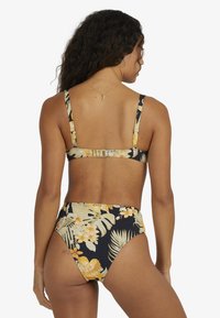 Svart bikini med gul blommönster; har breda axelband och högmidjad botten; slät textur och justerbar bakklämma.