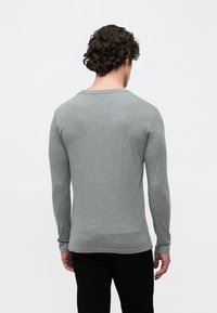 Hall halli puuvillane pikkade varrukatega särk, millel on ümar kaelus ja soonilised varrukaotsad, sile tekstuur ja kehasse istuv lõige.