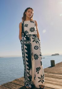 Conjunto de dos piezas con un patrón floral en blanco y negro, que incluye un top corto y pantalones de pierna ancha. Fabricado en tela ligera, con bolsillos.