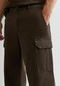 Bruine cargo broek met voor- en zijzakken, gemaakt van stevig materiaal, met een rechte snit en een gladde textuur.