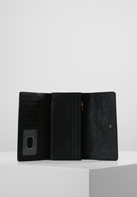 Portafoglio in pelle nera con diverse fessure per carte, una tasca con zip e una finestra trasparente per l'ID. Texture liscia e dettagli in metallo color oro.