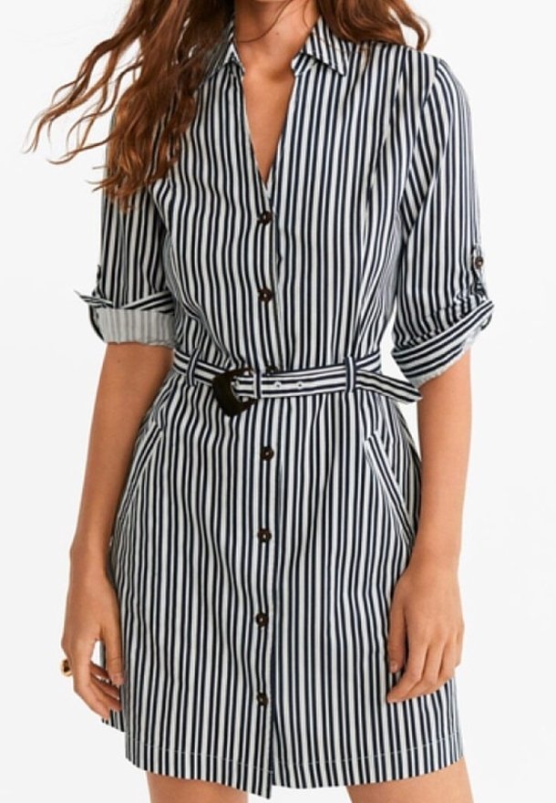 Abito camicia al ginocchio a righe verticali blu e bianche. Presenta una chiusura con bottoni sul davanti, maniche arrotolate e una cintura di tessuto in vita.
