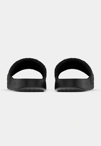 Μαύρα σανδάλια με φερμουάρ, ανοιχτή πλάτη και υφή στη σόλα. Κατασκευασμένα από λείο συνθετικό υλικό. Διαθέτουν ανάγλυφο λογότυπο κοντά στη φτέρνα.