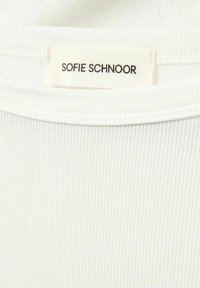 White ribbed textile with a soft texture, featuring a label that reads "Sofie Schnoor" in black font. Minimalist design emphasizes simplicity.
