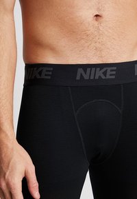 Black Nike men's underwear with a wide elastic waistband featuring the brand name. Textured fabric and a supportive design for comfort.
