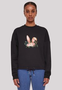 Schwarzer Sweatshirt mit einer zentralen Grafik von Kaninchenohren und Blumen. Hat lange Ärmel und einen Kordelzugsaum. Weiche Stofftextur.