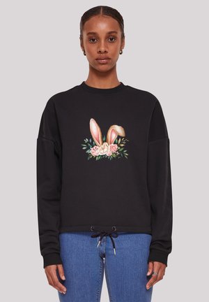 Black sweatshirt with a central graphic of rabbit ears and flowers. Features long sleeves and a drawstring hem. Soft fabric texture.