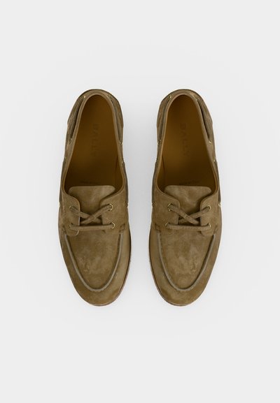 Ζευγάρι καφέ δερμάτινων μοκασίνων από σουέντ με σχέδιο moc toe και δερμάτινα κορδόνια, σε λευκό φόντο, από πάνω.