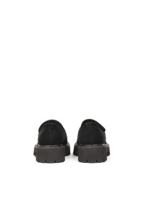 Black suede shoes with a chunky black rubber sole, featuring a backless design and rounded toe. The texture appears smooth and soft.