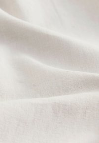 Witte linnen stof met een gladde, gestructureerde oppervlakte, die subtiele weefvariaties en een zachte draping toont.