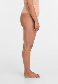 Nackter hochgeschnittener Body, glatte Textur, enganliegendes Design, nahtlose Kanten und breite Träger, auf einer Seitenansicht eines Models dargestellt.