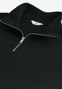 Zwarte ritssluiting pullover van een textuur katoenmix. Heeft een hoge kraag en een zilveren rits, met een label waarop "NEXT" staat aan de binnenkant.