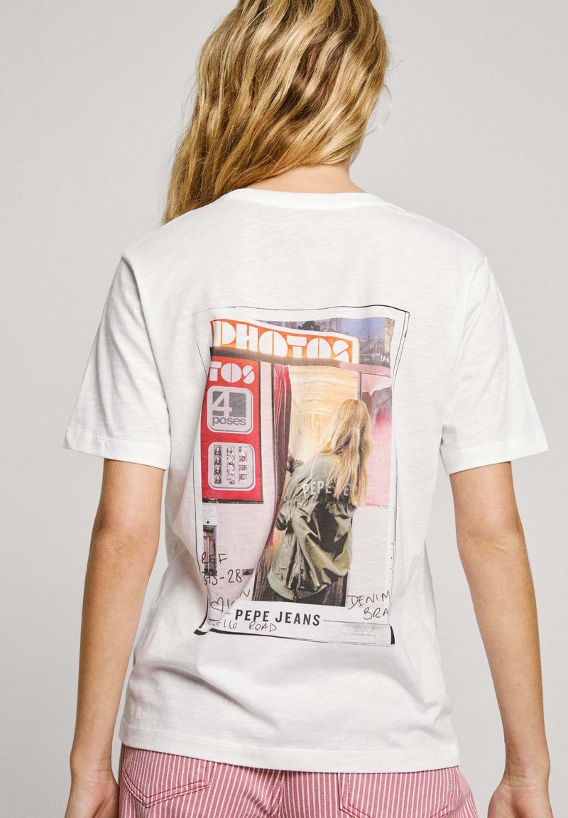 Bílý bavlněný tričko s potiskem na zadní straně. Design zobrazuje scénu z fotokoutku s textem a ilustrovanou postavou.