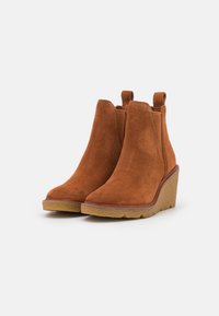 Pair of brown suede wedge ankle boots with pull tabs and rubber crepe soles, displayed against a plain white background.