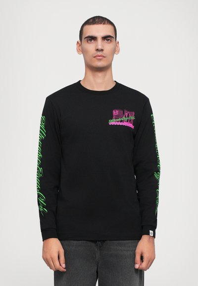T-shirt preta de manga longa com um gráfico em neon rosa no peito e texto verde nas mangas, feita de material de algodão suave.