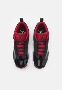 Schwarze und rote Sneakers mit einer glänzenden Lackleder-Spitze, Mesh-Stoff und Schnürsenkeln. Besitzt markante Akzente und eine Zuglasche an der Ferse.