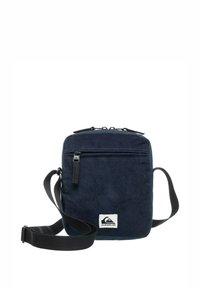 Bolso de hombro de pana color marino con un diseño plano, compartimento principal con cremallera, bolsillo frontal, correa ajustable y una placa con el logo en la parte inferior.