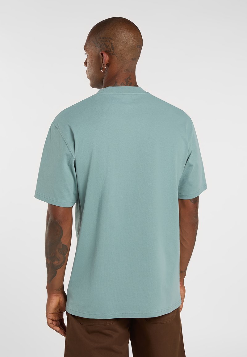 Maglietta a maniche corte di colore azzurro chiaro, realizzata in cotone. Presenta una vestibilità comoda e una scollatura arrotondata. La vista posteriore mostra cuciture minime e una texture morbida.