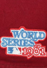 Roter Stoff mit strukturiertem Oberflächen, der den gestickten Text "WELTMEISTERSCHAFT" in Blau und "1981" in Rot zeigt. Logodetail von der Major League Baseball.