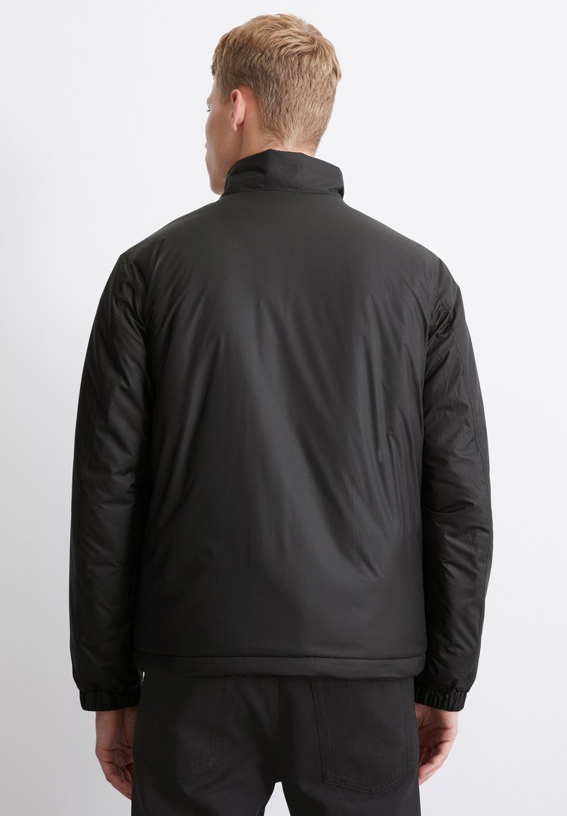 Schwarze Daunenjacke mit hohem Kragen, elastischen Bündchen und einer glatten, matten Oberfläche. Verfügt über einen lässigen Schnitt und kontrastierende Nähte.