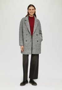 Grijze dubbelzijdige wollen blend jas met een opstaande kraag, twee voorkruiszakken en een gestructureerde stof. Gepaard met donkere wijde broek en zwarte laarzen.