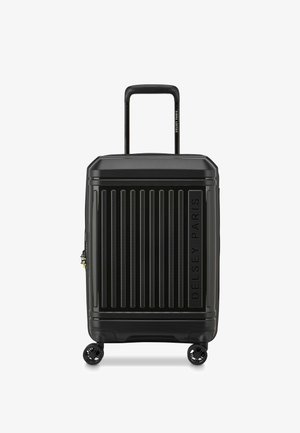 Valise rigide noire avec des rainures verticales, poignée rétractable, quatre roues multidirectionnelles et un logo bien visible sur le côté.