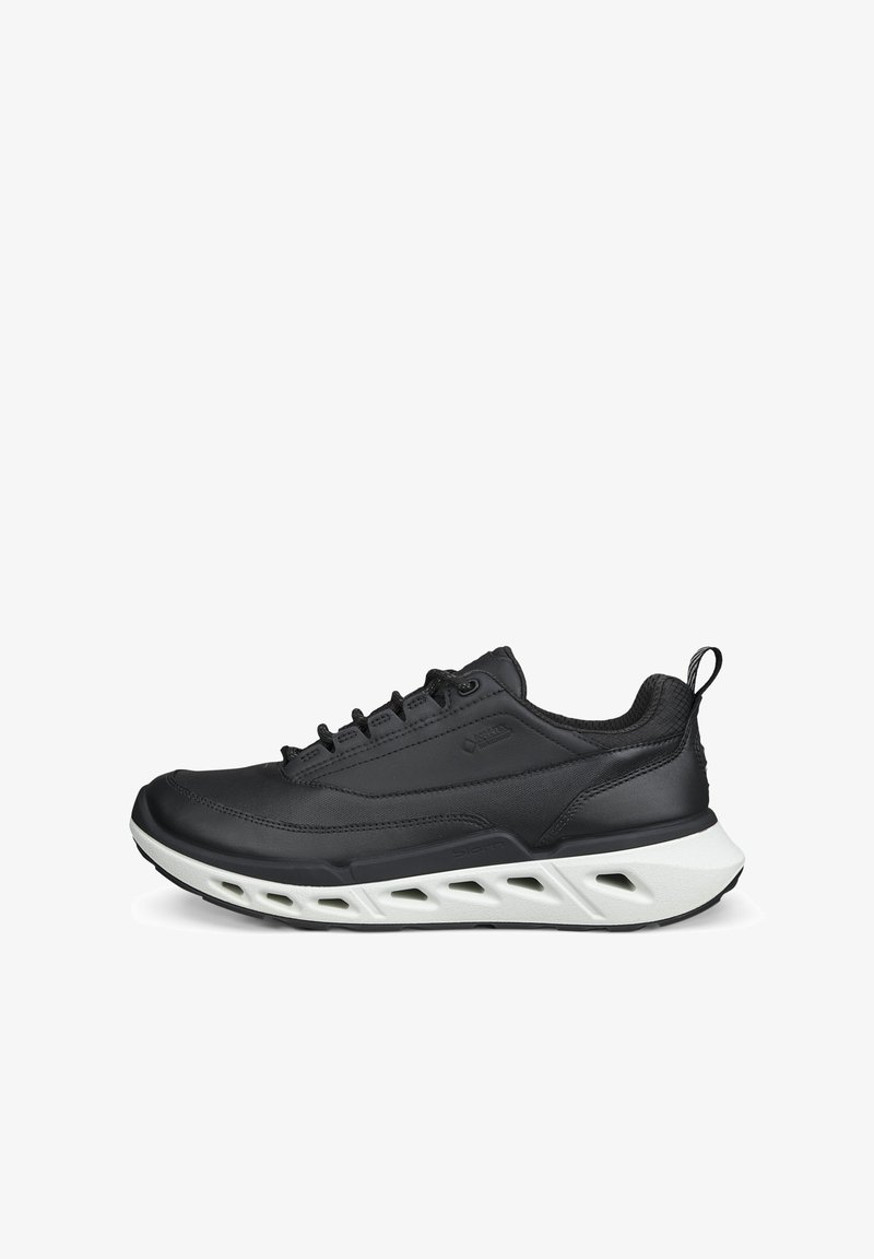 Zwarte lage sneaker met vetersluiting, gevoerde kraag en witte geventileerde zool, zijaanzicht op witte achtergrond.