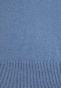 Ljusblå stickad tröja med slät textur och ribbad nederkant. Tätt stickad design utan synliga mönster eller detaljer i metall.