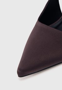 Čevlji s koničastim nosom v temno vijolični tkanini. Eleganten dizajn vsebuje gladko teksturo in nizek zgornji del, ki razkriva črno notranjost.